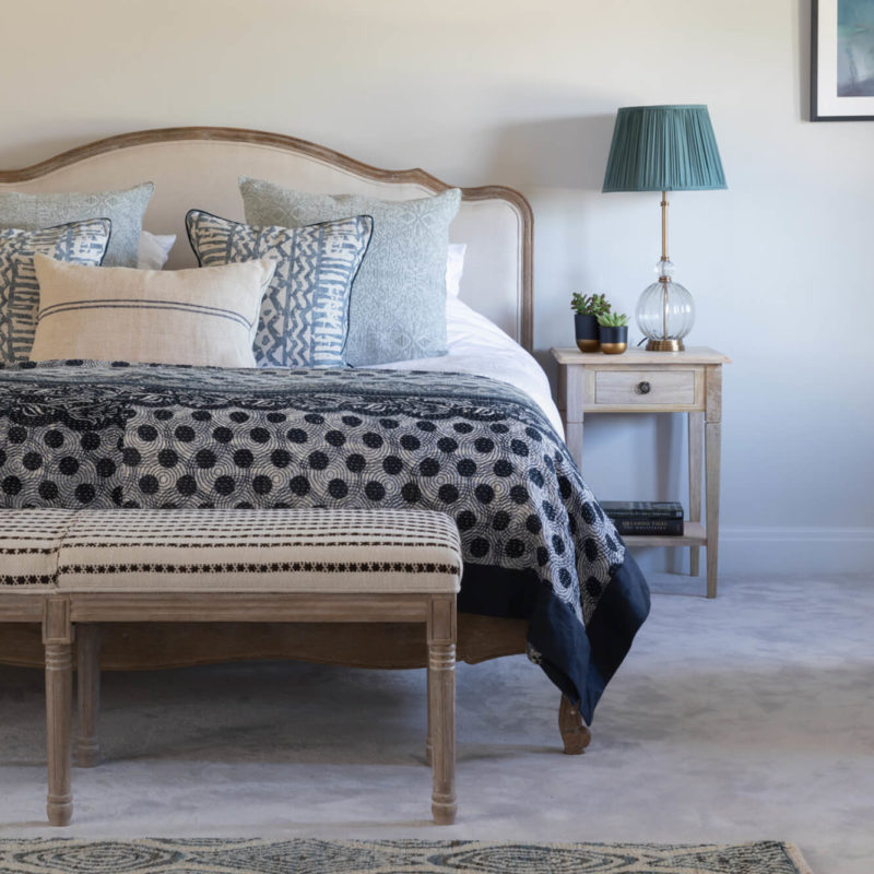 Blue bedroom decor with rug and bench at foot of bed