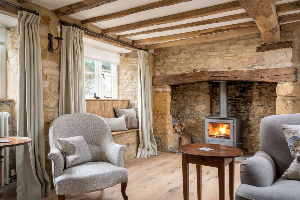 antique furniture in Cotswold living room with stone walls and fireplace