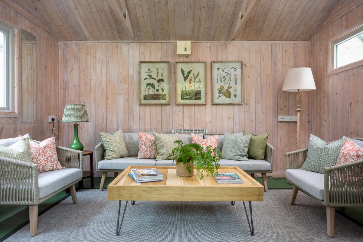 Garden room with sofa and armchairs, doff table and antique prints.