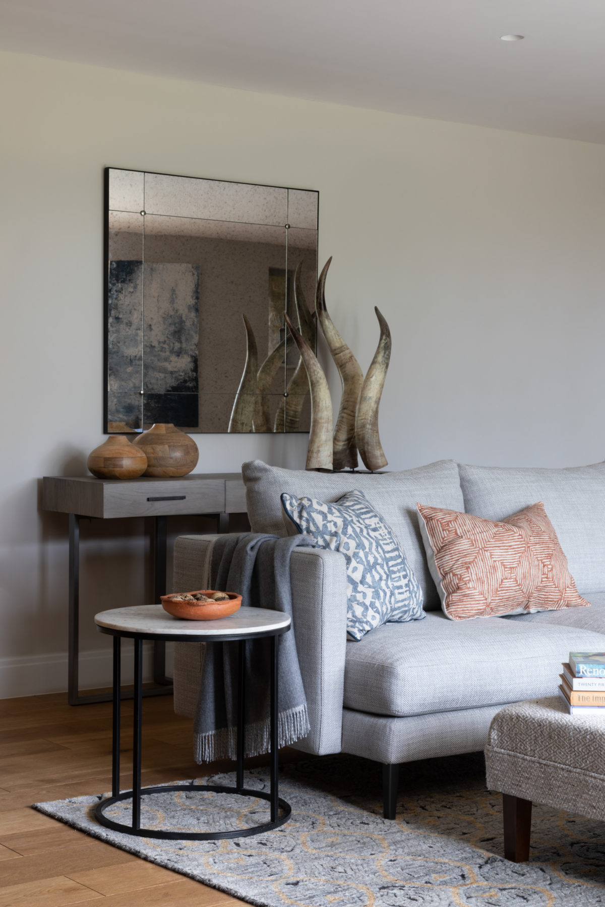 Antique glass mirror in living room. Marble side table. Accessories in groups Blue and orange cushions on corner sofa