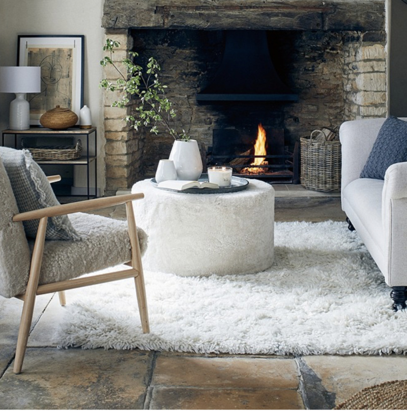 living room with inglenook fireplace and boucle footstool