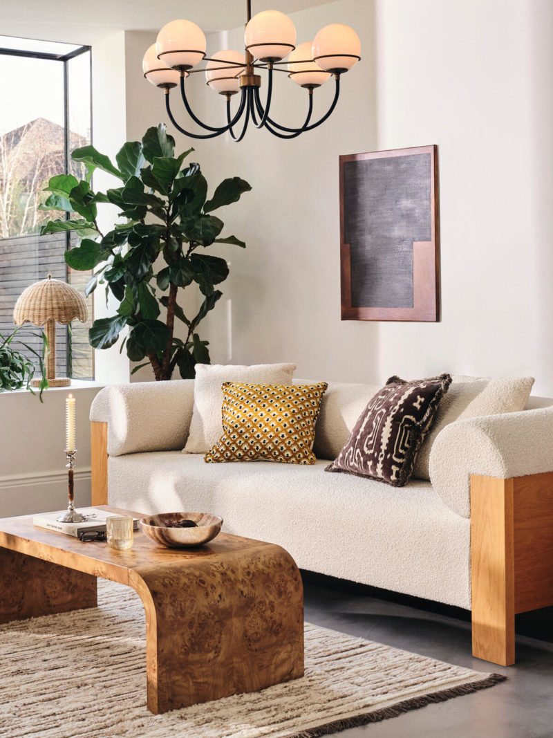 Mid-century sitting room with multi arm chandelier, cream sofa and wood coffee table