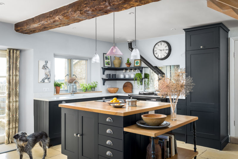 Black kitchen with quartz work surface and oak top on the island unit. Glass pendant lights