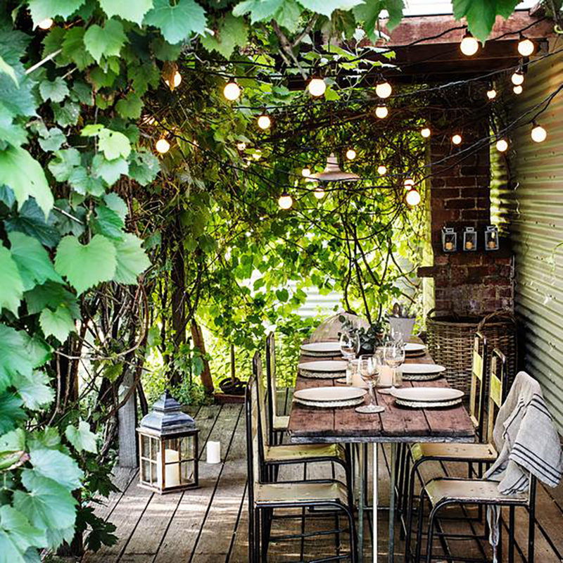 outdoor dining table & chairs with hanging garden lights in loggia