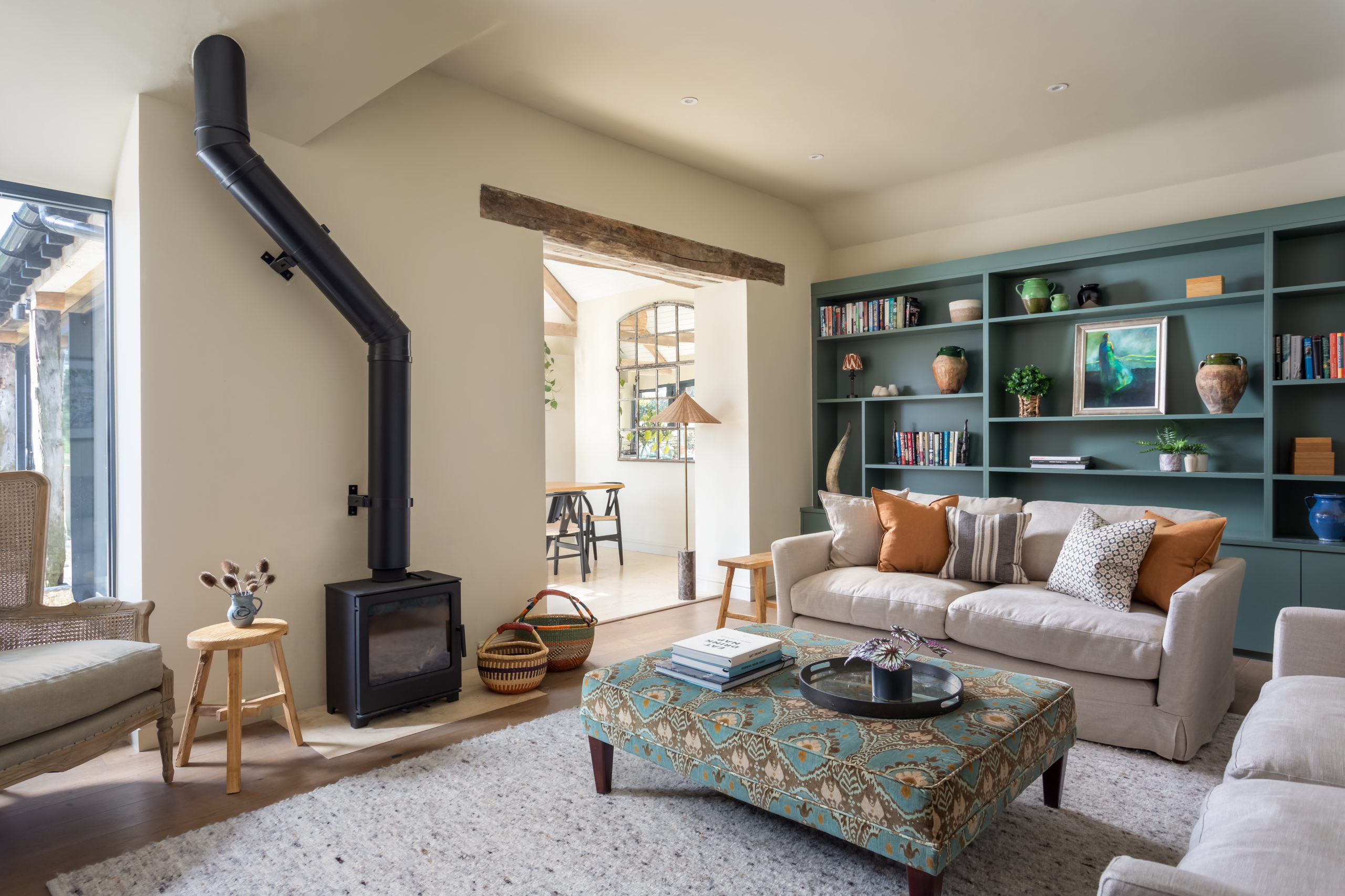 sitting room with fireplace, footstool and bookcase. Central rug grounds the sofas and footstool.