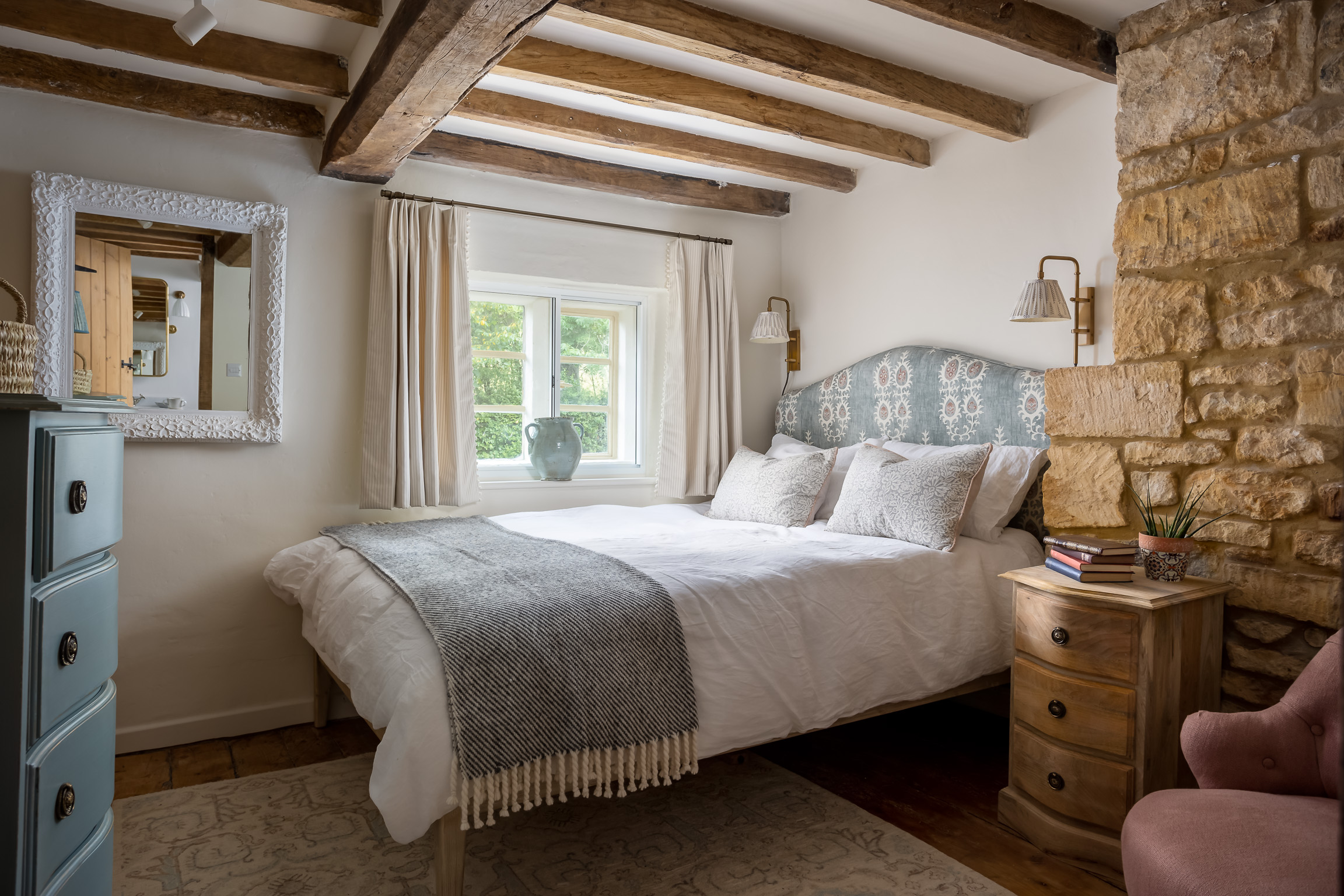 King size bed & patterned headboard in beamed cottage bedroom