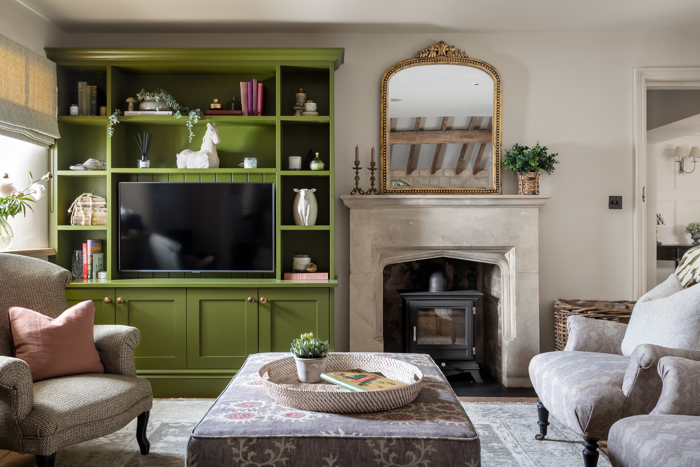 Livign room with green bookcase, large footstool, sofa, fireplace & overmantel mirror and 3 armchairs