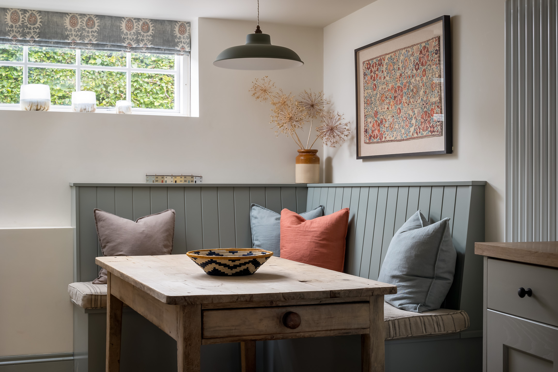 Kitchen dining table with built-in seats & pendant light. Roman blinds in Lewis & Wood's Tribal fabric