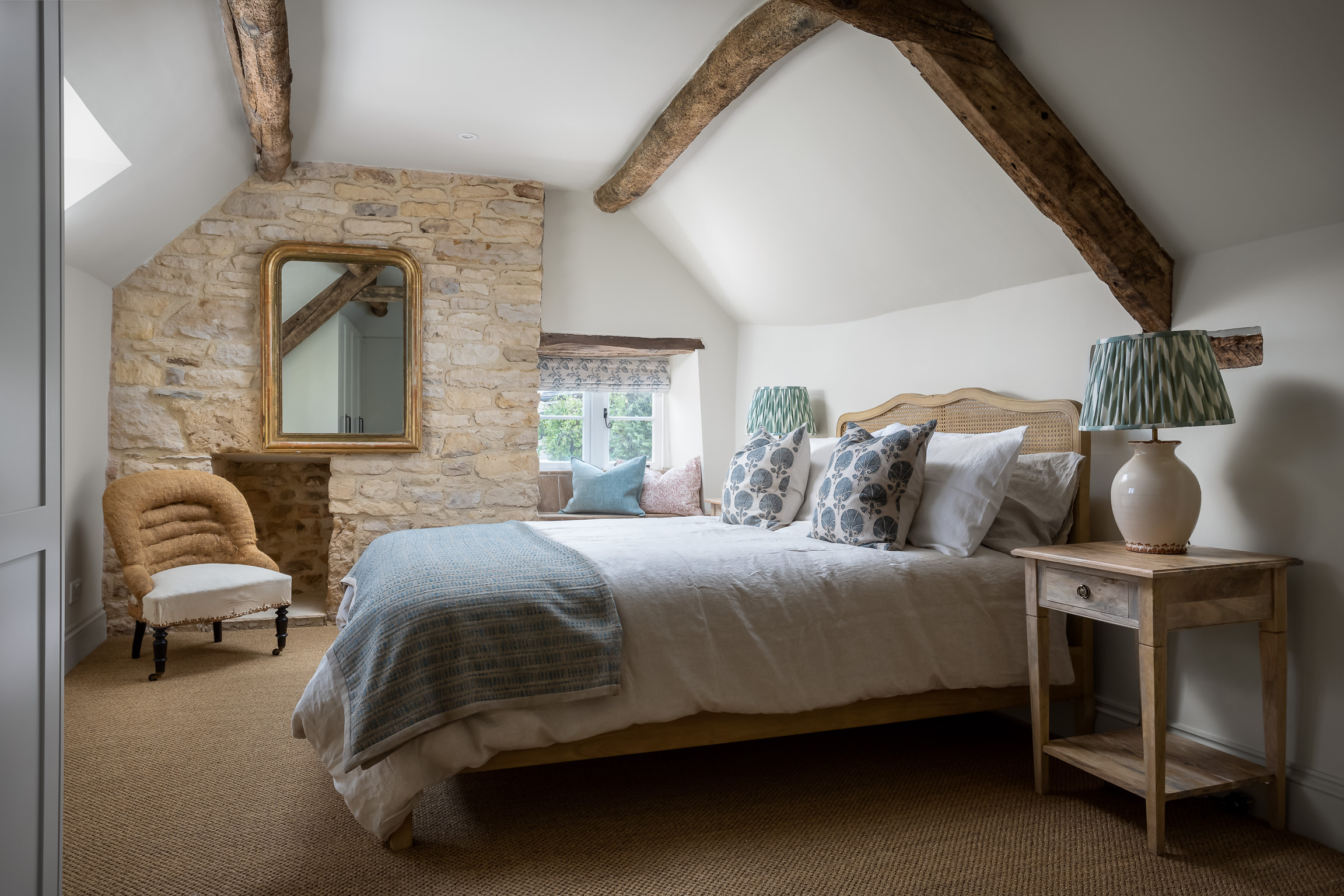 Master bedroom with wood beams, king size bed with rattan headboard, sisal flooring.