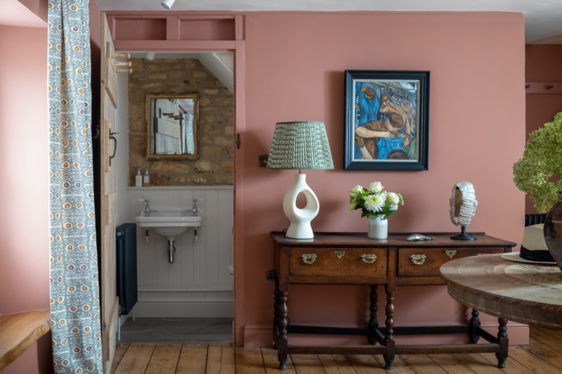 Cloakroom with stone wall & antique mirror. oak dresser in entrance hall, modern stone lamp & green shade