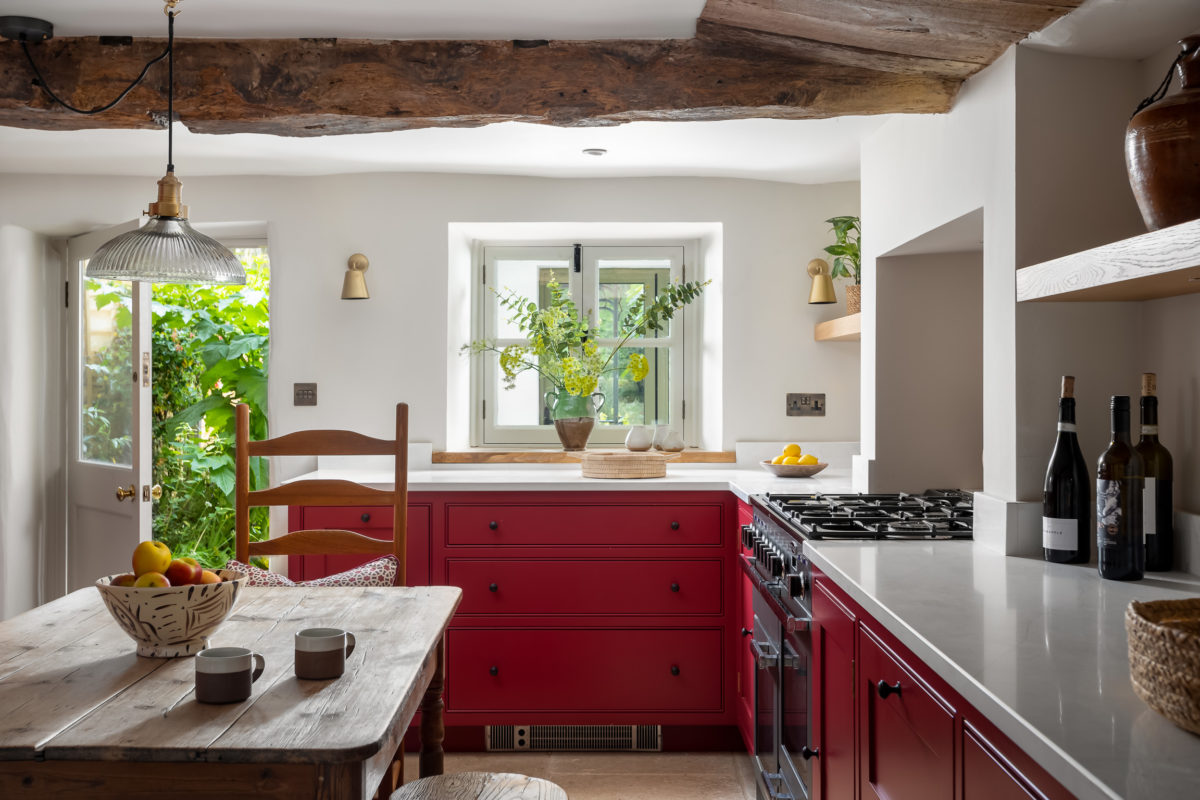 Country kitchen. Units in Farrow & Ball radicchio. Pine farmhouse table, Antique brass wall lights, antique rug