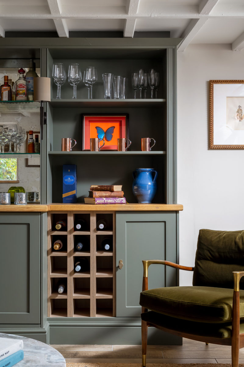 Built in bar cabinet in olive green with antique mirror back, green velvet mid century armchair and rug