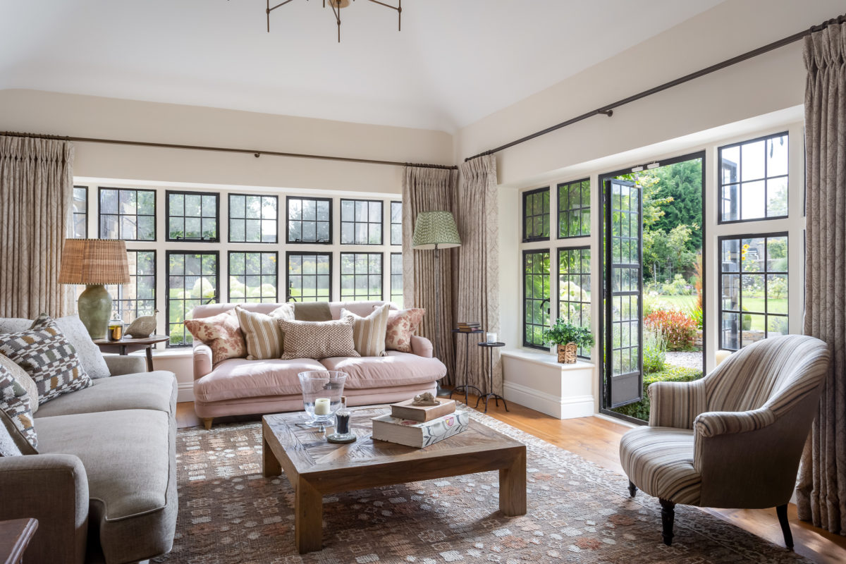 Farmhouse sitting room in green brown & pink; 2 sofas, cushions, rug, coffee table, floor lamp & table lamps on antique side tables