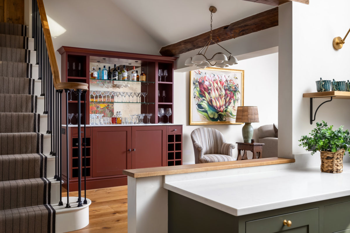 Built-in bar with antique mirror back, glass shelves, downlights, wood floor to dining area, original art, pendant light, table lamp on antique oak side table. Metal and oak staircase