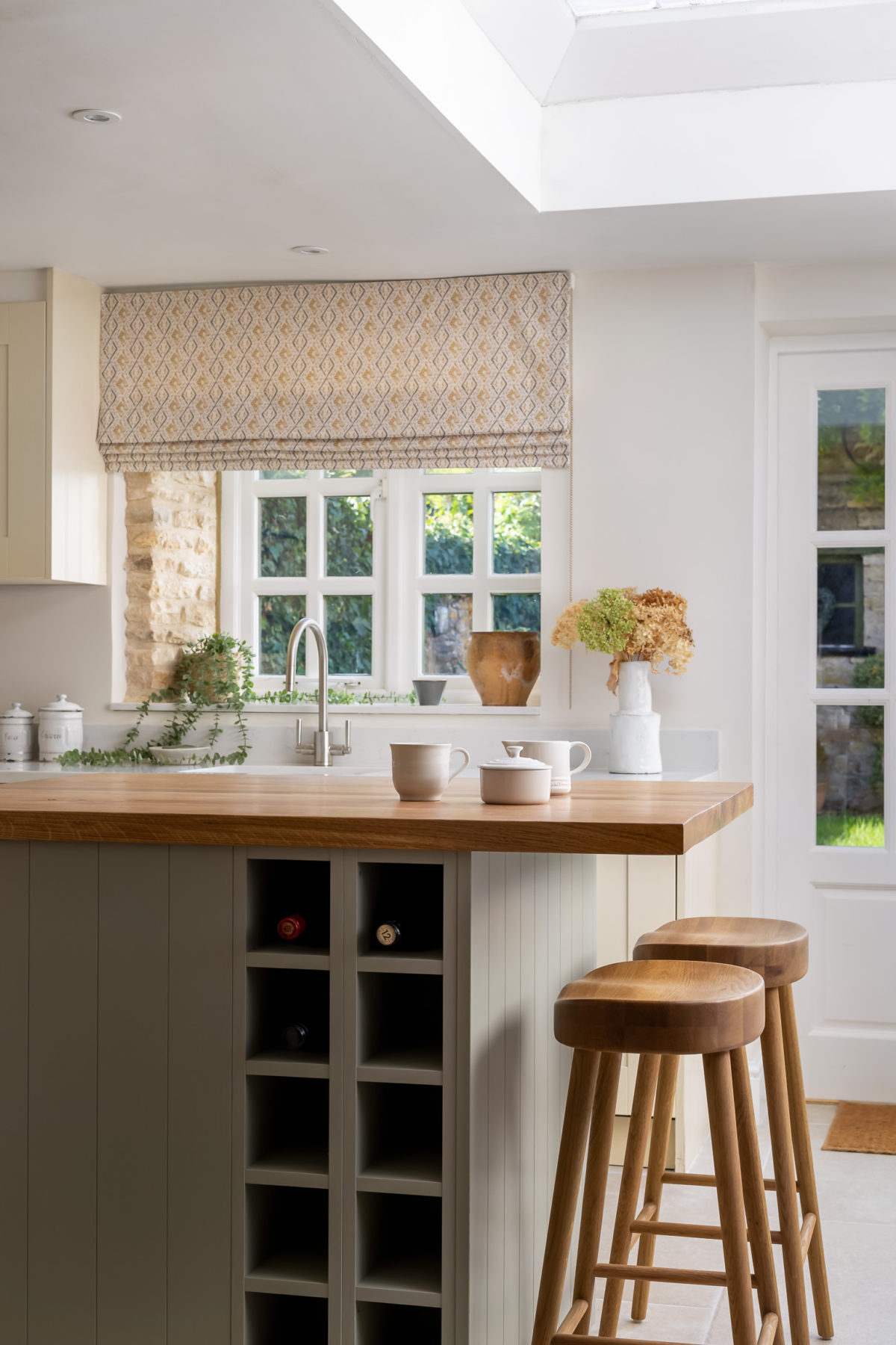 Kitchen island in free with oak worktop, oak bar stools. Roman blind in straw colour.