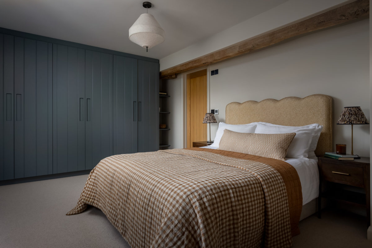 Guest bedroom with built-in wardrobe in Farrow & Ball De Nimes; pendant light, upholstered bed in amber, wool carpet